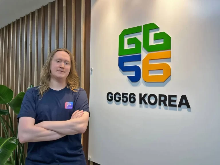 Nikita, web developer, standing next to GG56 Korea logo in their offices