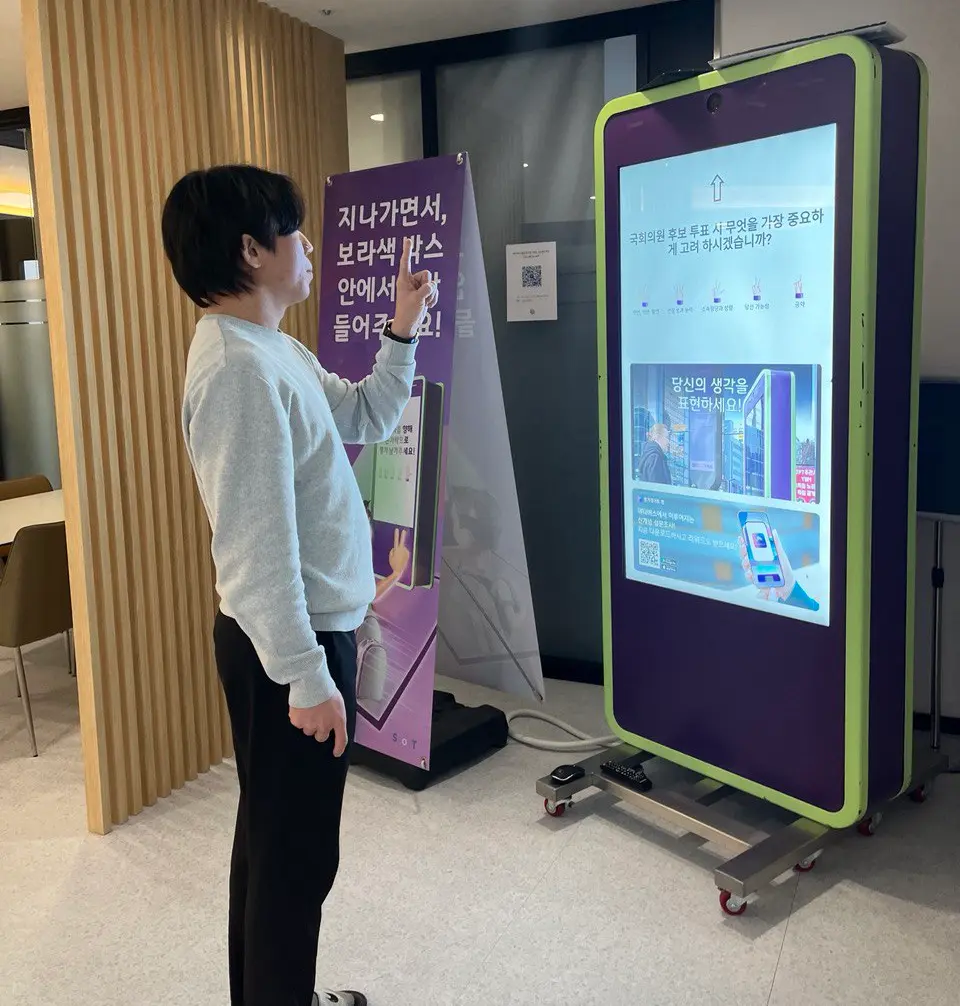 An employee of GG56 Korea standing next to the FingeRate bot